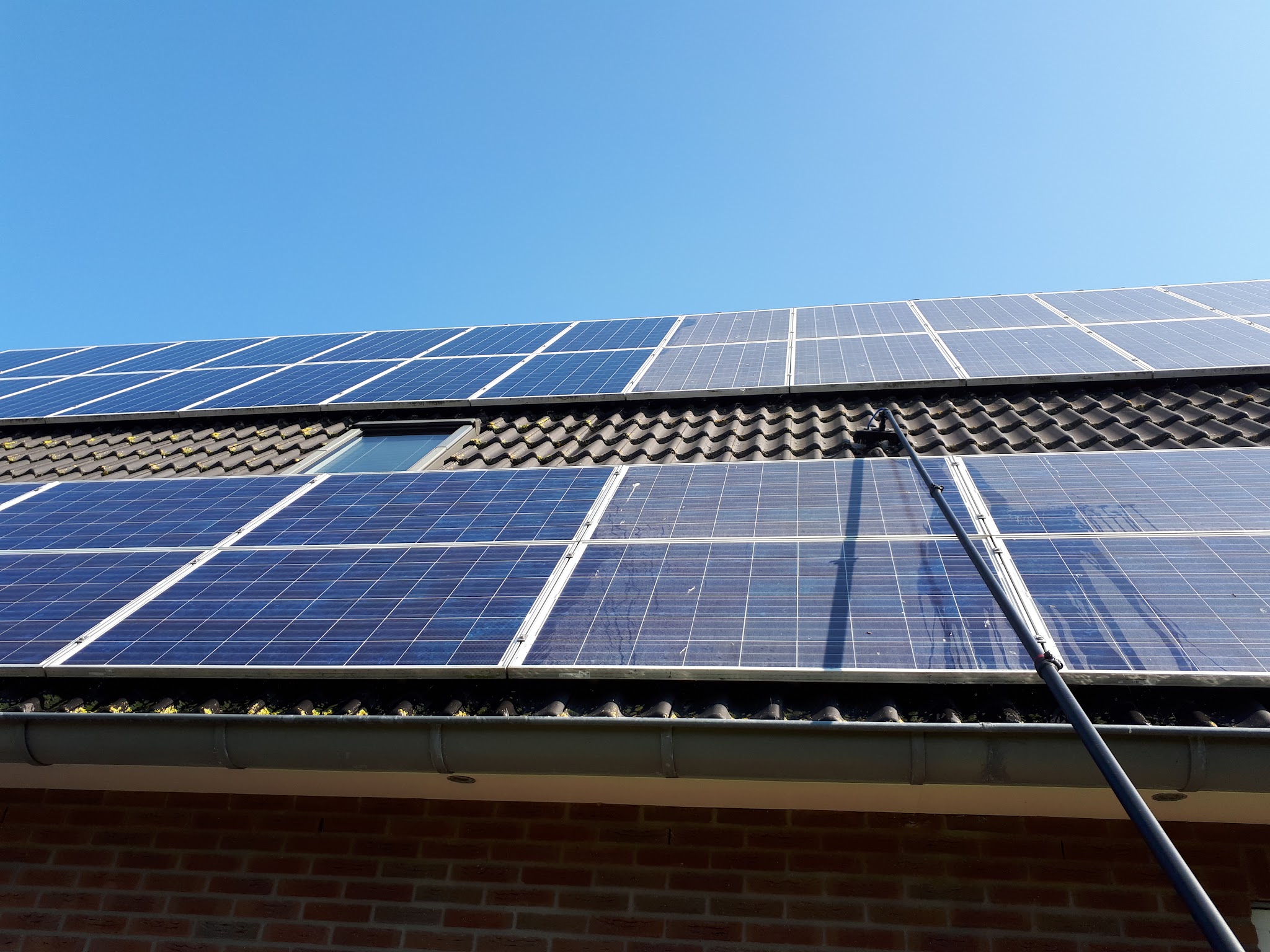 Zonnepanelen op een dak worden gereinigd met de telescoopsteel