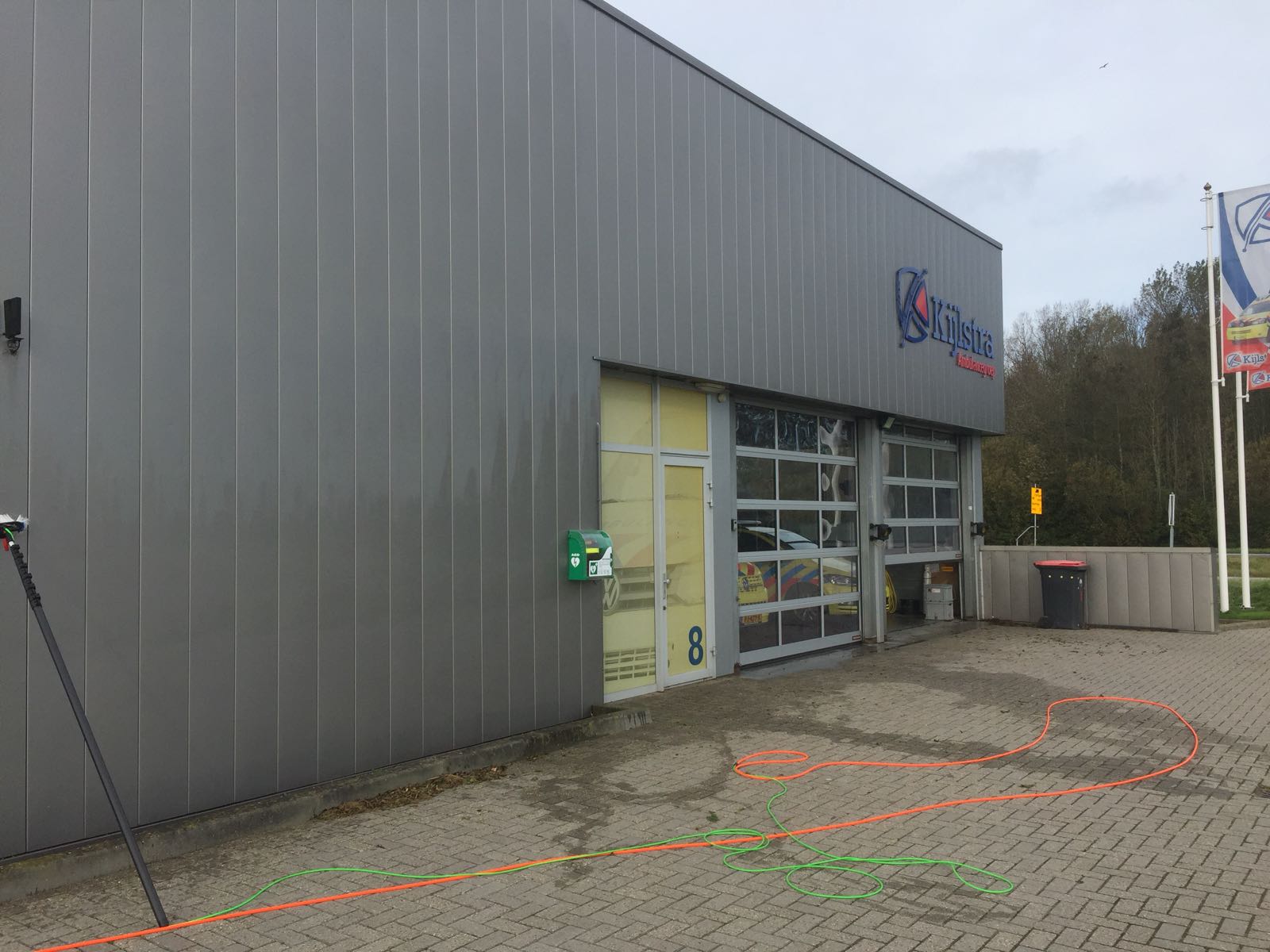 Bedrijfshal met stalen gevelbeplating, de hogedrukslangen liggen klaar op de bestrating